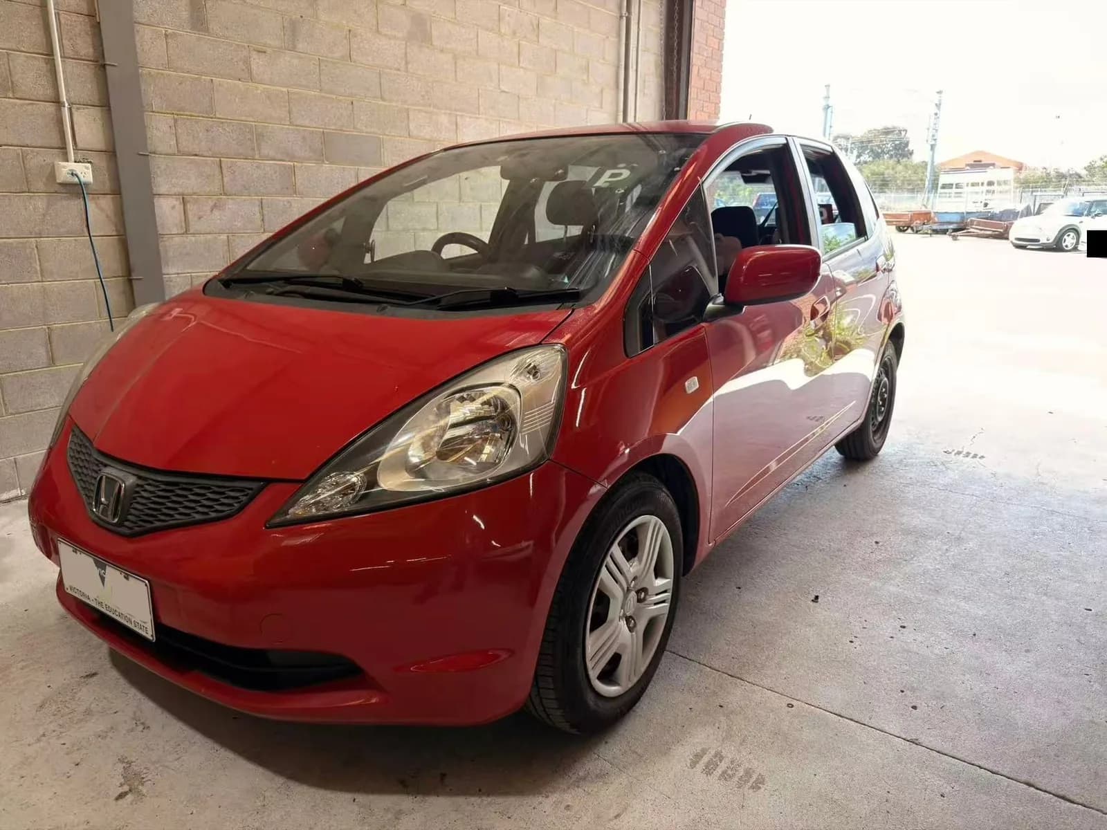 Red 2010 Honda Jazz at the C1 Automotive workshop in Oakleigh South, number plates redacted