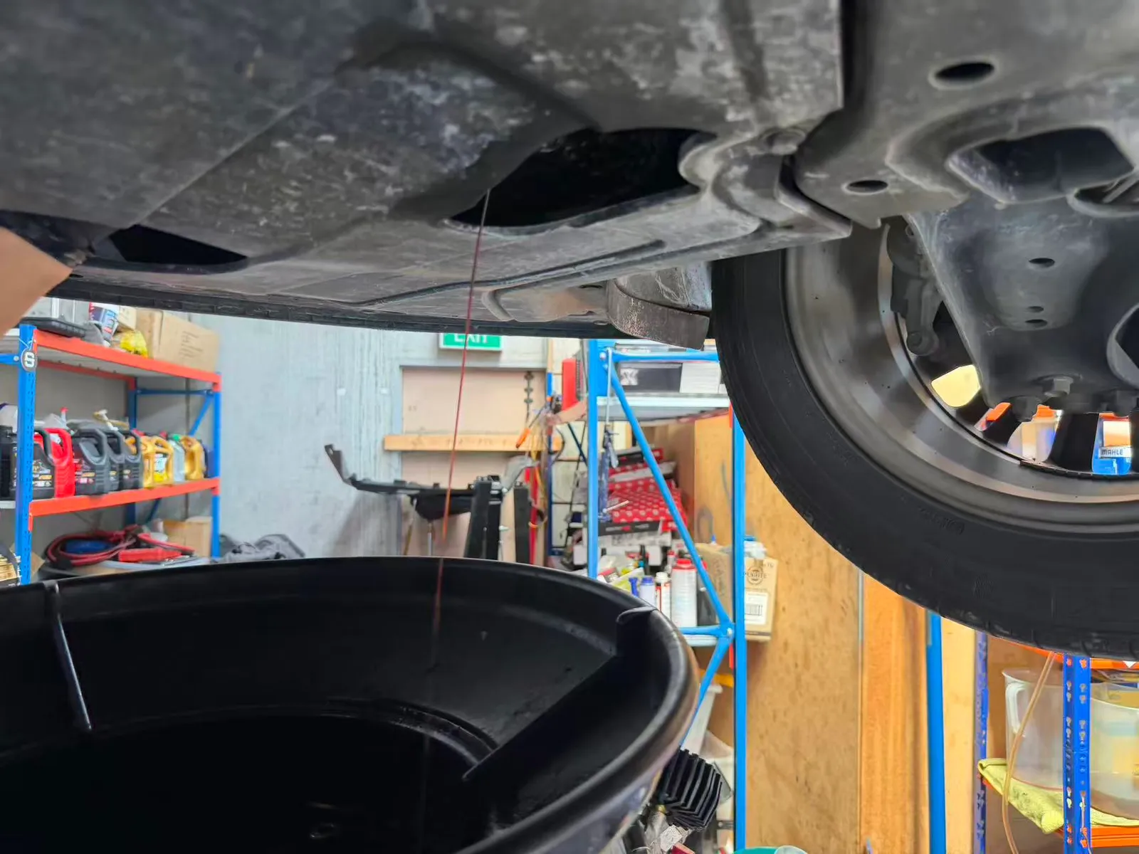Old engine oil draining from the sump of a Hyundai Kona into a drain tray