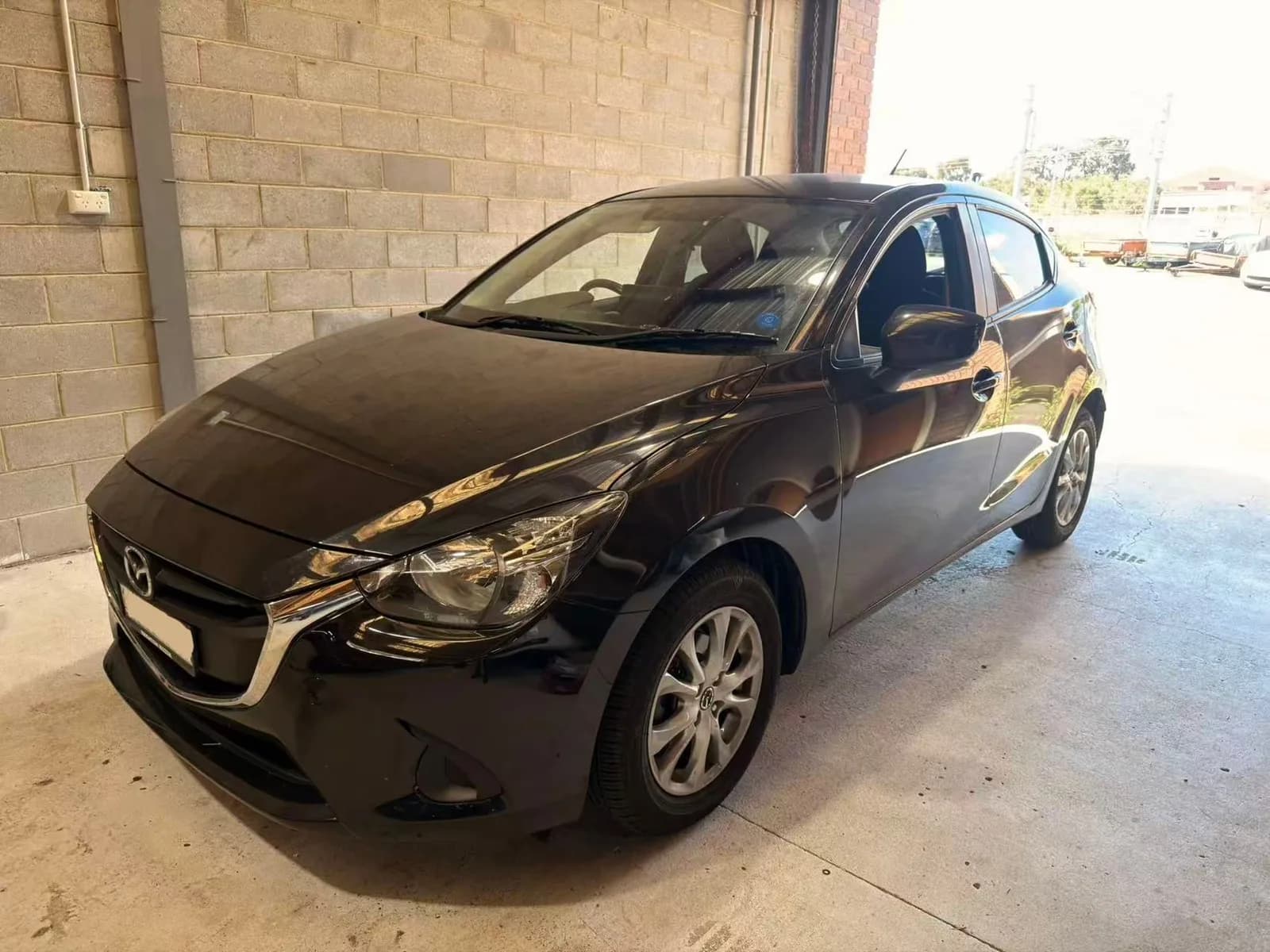 Black 2015 Mazda2 hatch at the C1 Automotive workshop in Oakleigh South, number plate redacted