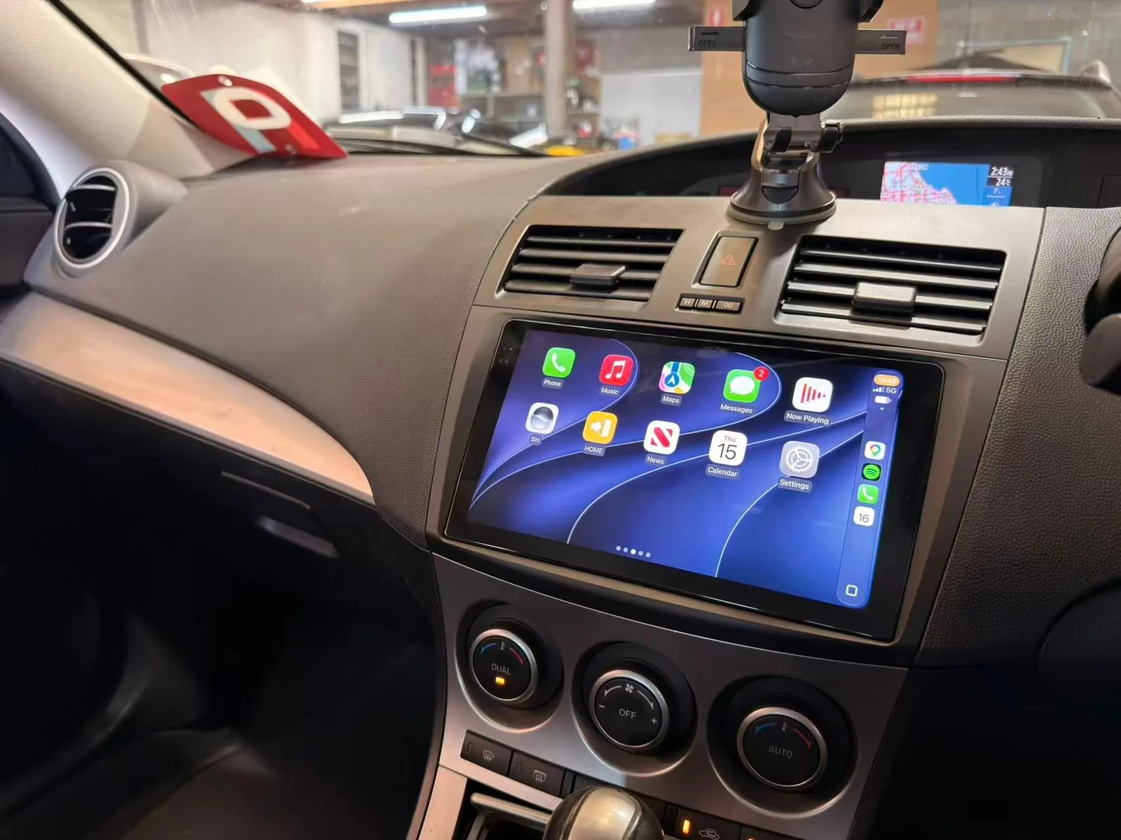 Apple CarPlay home screen on a touchscreen head unit in the factory opening of a 2010 Mazda3