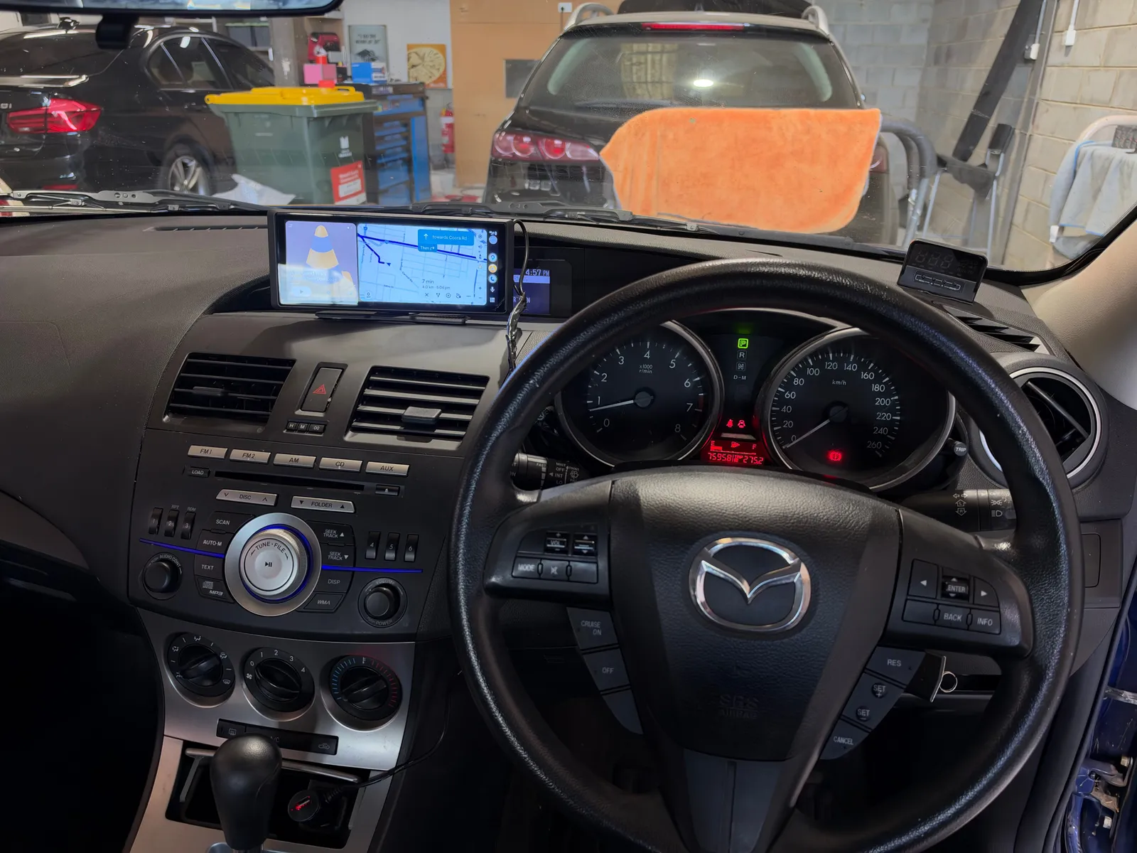 Wide Apple CarPlay and Android Auto screen on top of the dash of a 2011 Mazda3, with a parking sensor display on the right of the dash
