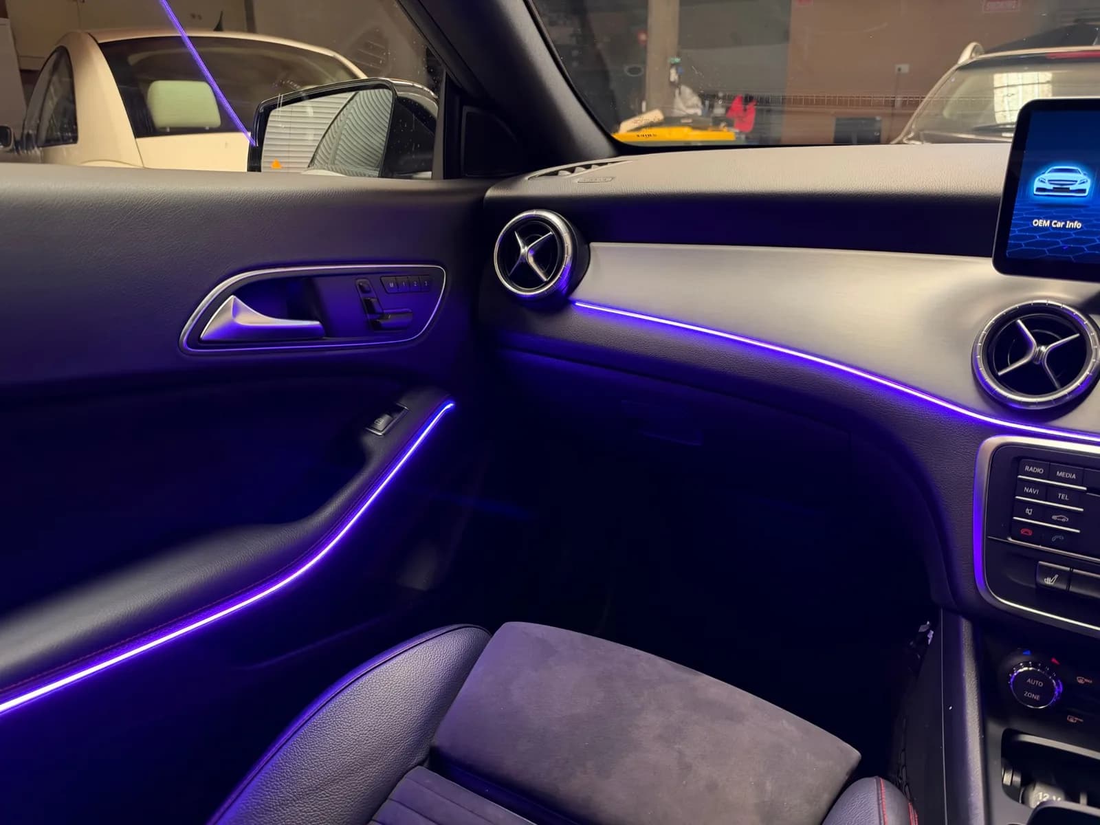 Purple ambient lighting along the passenger door and dash of a 2015 Mercedes-Benz CLA, with the OEM Car Info screen showing