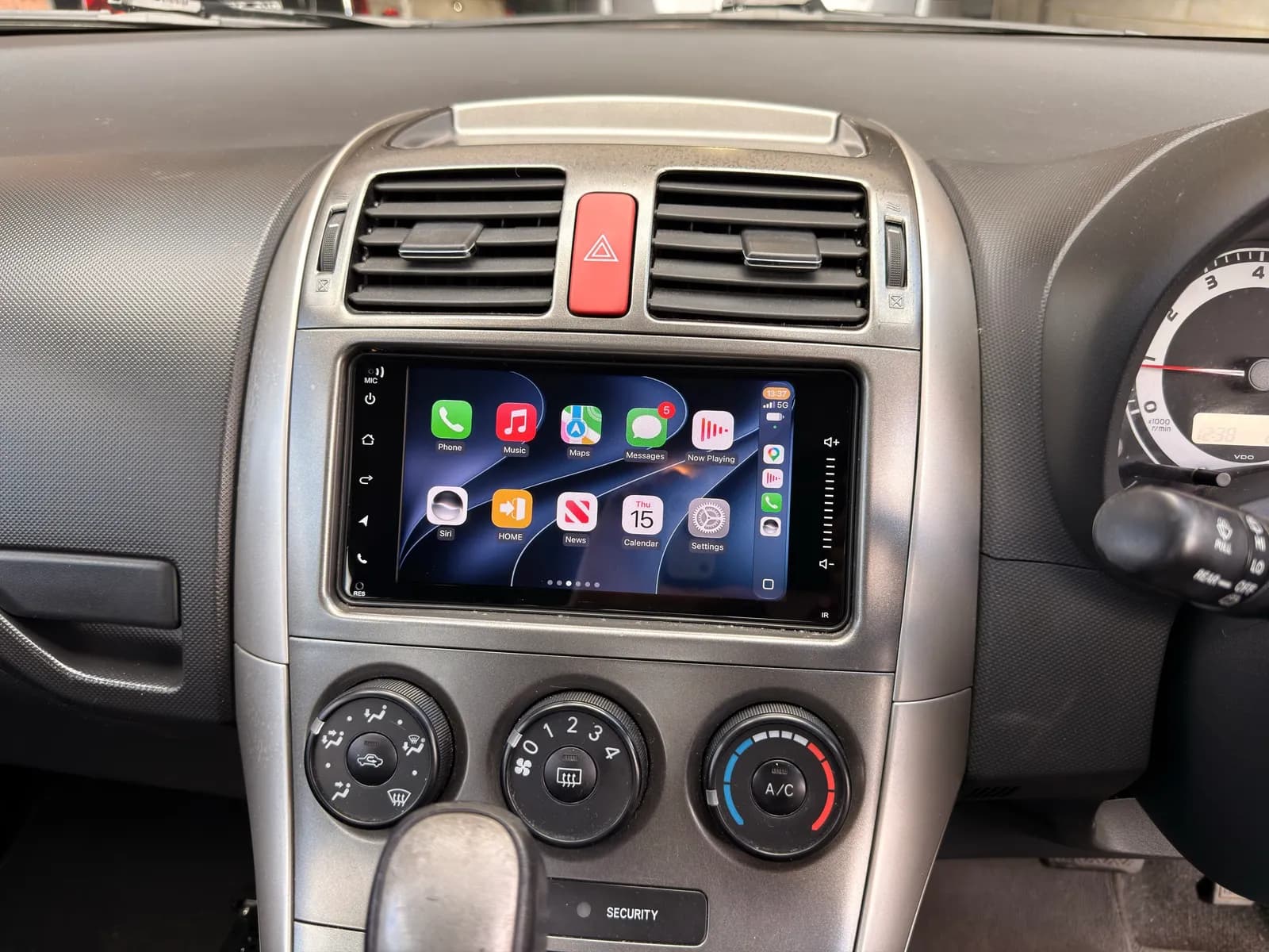 Apple CarPlay home screen on a touchscreen head unit fitted in the factory opening of a 2009 Toyota Corolla
