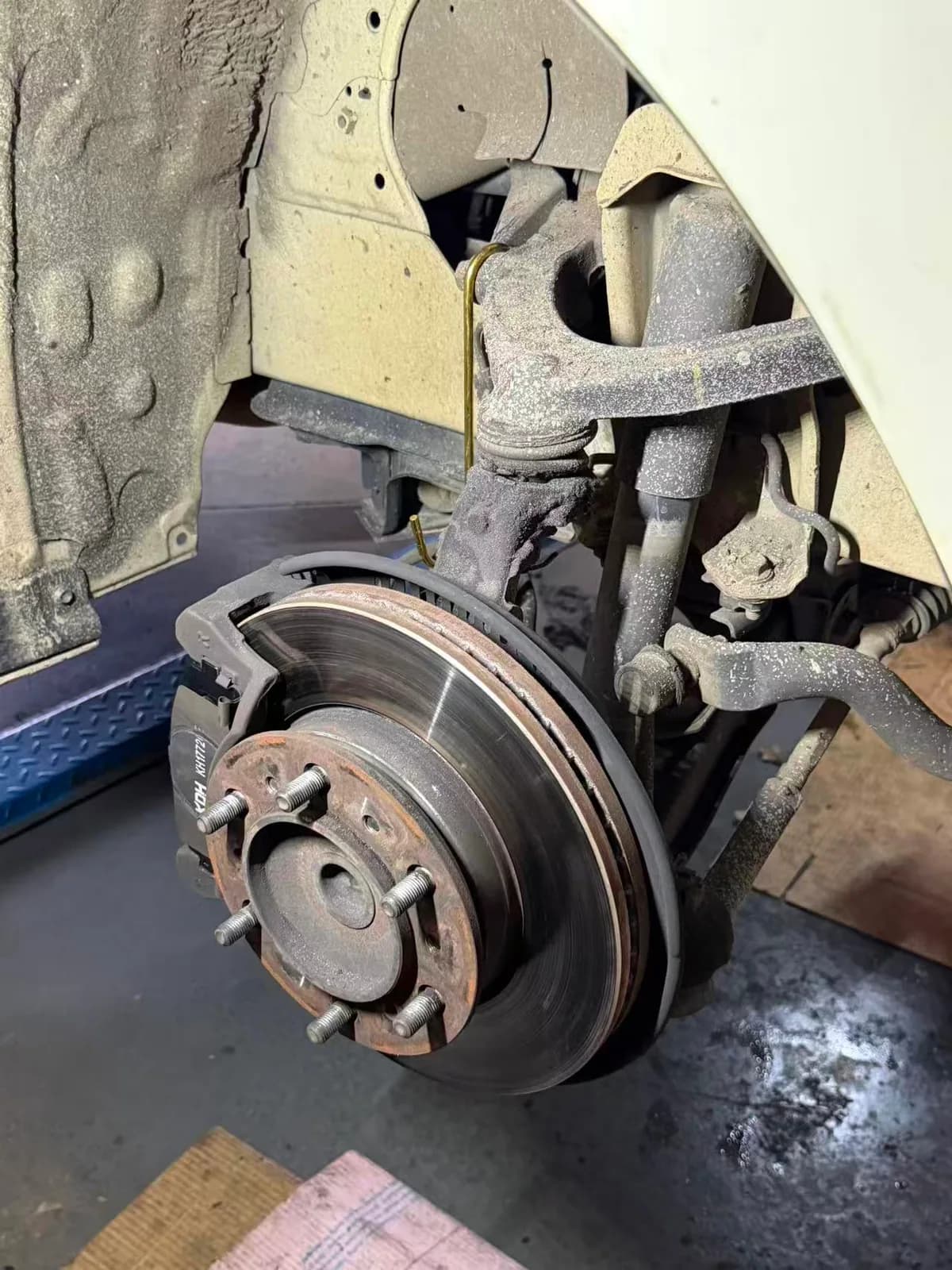 Toyota HiAce front brake rotor, caliper and suspension exposed for inspection