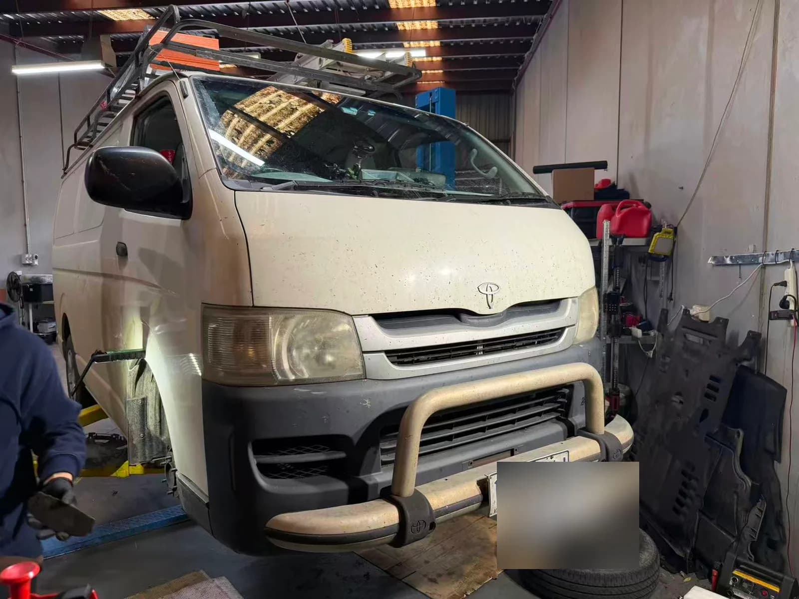 Toyota HiAce work van on a workshop lift for servicing and brake repairs in Oakleigh South with the number plate redacted