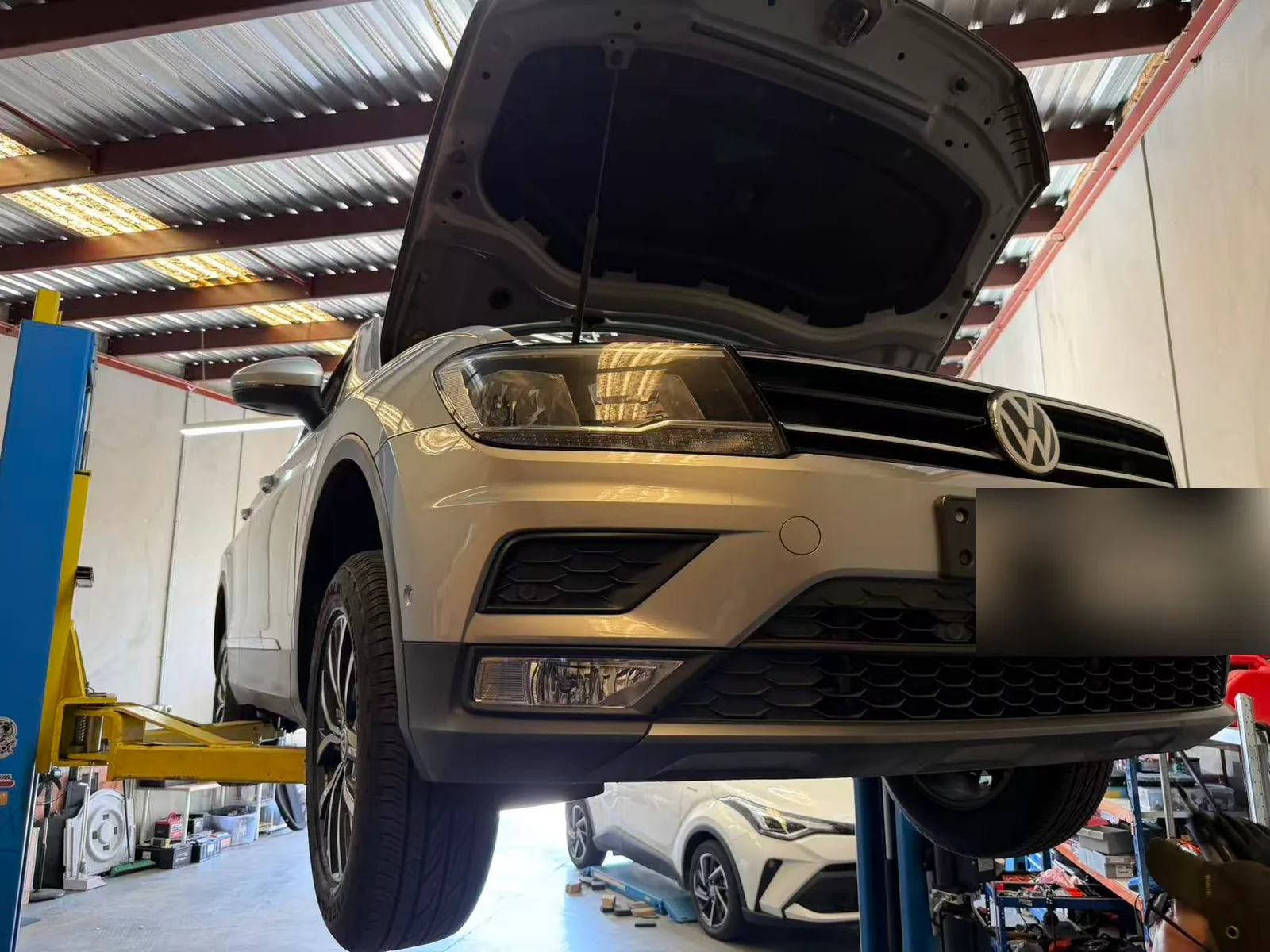 Volkswagen Tiguan raised on a workshop lift for logbook servicing at C1 Automotive in Oakleigh South with the number plate redacted